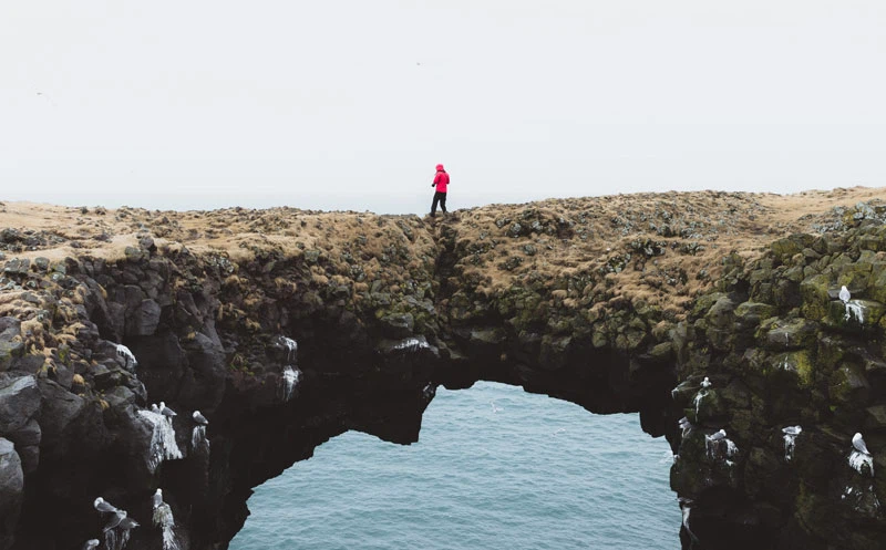 A human walking on a rock in front of water
