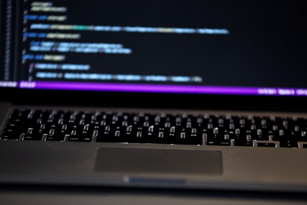 Source code on a developer keyboard and screen