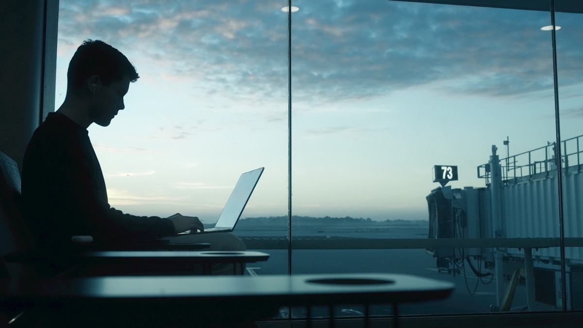 An engineer working on a laptop at an airport gate before sunrise