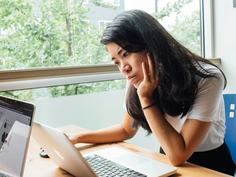 A woman sitting and looking into a laptop